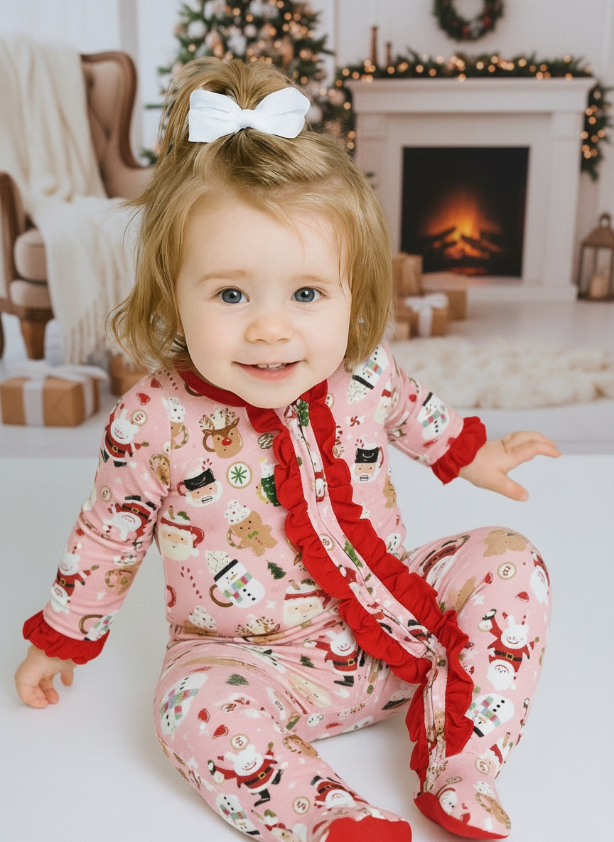 Child wearing Christmas-themed pajamas in a festive living room with a fireplace and decorated tree.