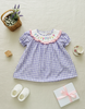 Children's purple checkered dress with floral collar on a light background